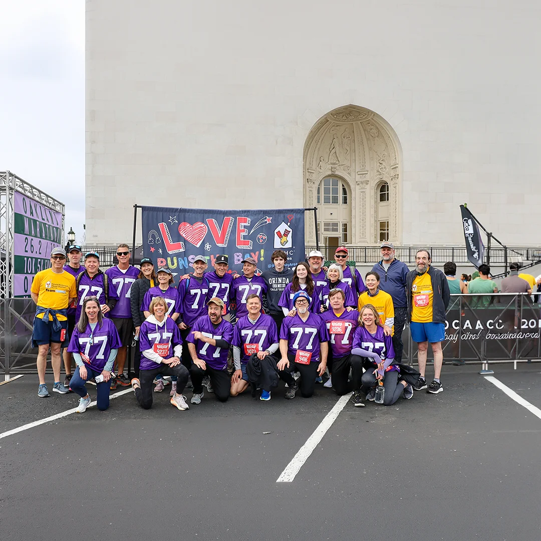 Group of RMHC Bay Area supporters in purple jerseys pose together at the Oakland Marathon, raising funds for families with seriously ill children.